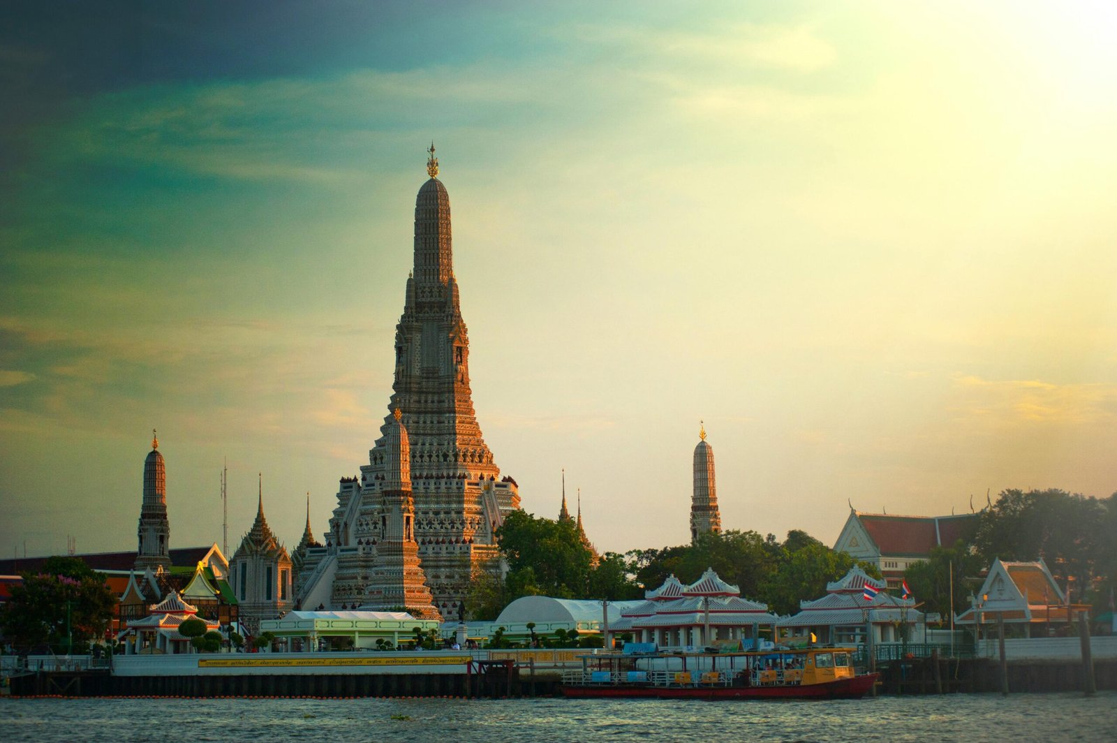 Stunning sunset view of Wat Arun temple by the Chao Phraya River in Bangkok, Thailand.
